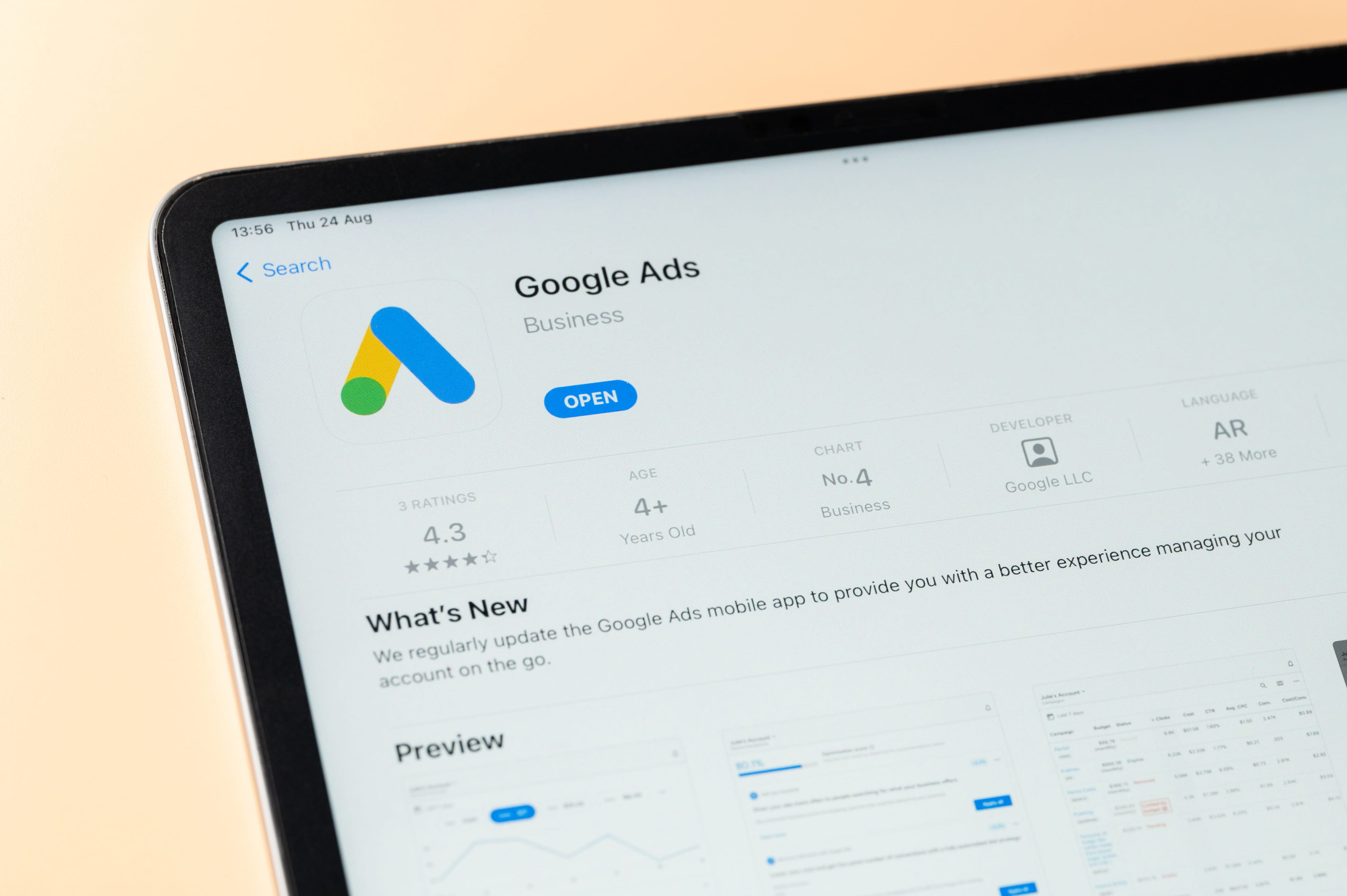 Close-up of a tablet screen displaying the Google Ads app page in an app store, showing the Google Ads logo, app rating, and an “Open” button.